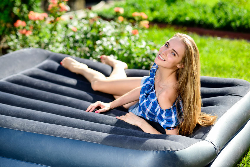 happy young woman lying on the matrass in the garden